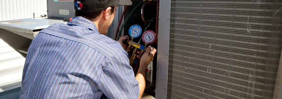 HVAC technician servicing a condenser unit in Mahomet