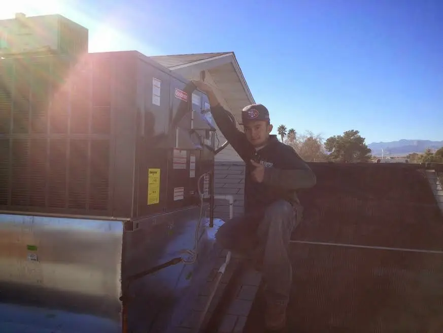 HVAC technician performing Heat Pump Repair on a rooftop unit in Mahomet